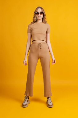 Genç duygusal bir kız, öğrenci pozu, dans turuncu arka planda izole edilmiş. Güzellik, sanat, moda, gençlik, tek renk kavramı