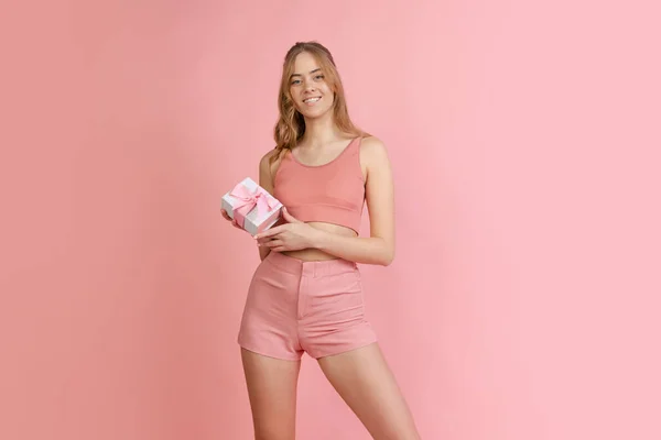 Monochrome portrait of young attractive woman in shorts and crop top isolated on pink background. Concept of beauty, art, fashion, youth — Fotografia de Stock