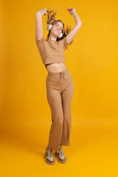 One young emotional girl, student posing, dancing isolated on orange background. Concept of beauty, art, fashion, youth, monochrome — Fotografia de Stock