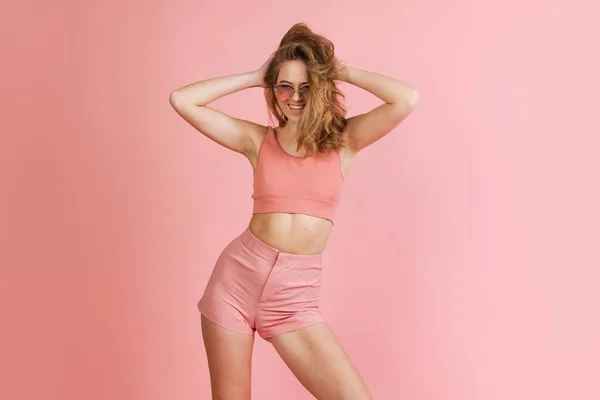 Retrato monocromático de mujer joven atractiva en pantalones cortos y top de corte aislado sobre fondo rosa. Concepto de belleza, arte, moda, juventud — Foto de Stock