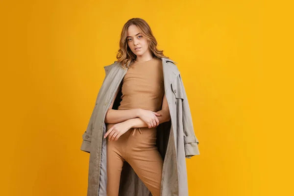 Emotional girl, student in costume and raincoat posing isolated on orange background. Concept of beauty, art, fashion, youth, monochrome — Stok fotoğraf