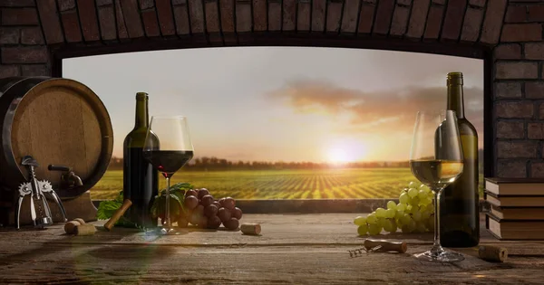 Still life with wine glasses, bottles, grapes on wooden table in wine cellar. Panoramic window view of lush vineyards at sunset. — Foto de Stock