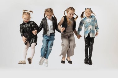 Mutlu okul ve anaokulu çocukları, gri stüdyoda izole edilmiş güzel kızlar. Güzellik, çocuk modası, eğitim, mutlu çocukluk kavramı.