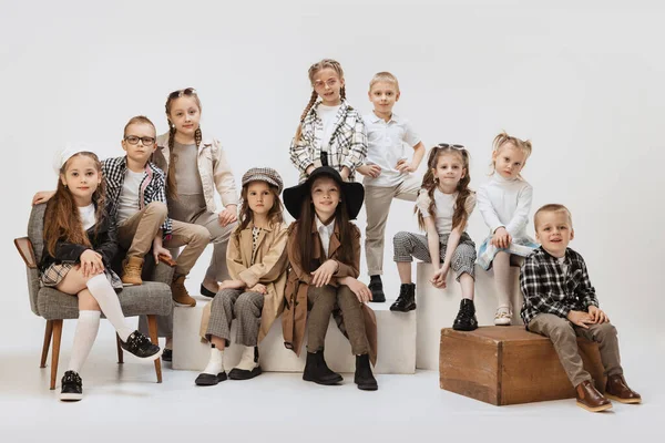 Bir grup güzel çocuk, modern kıyafetler içindeki küçük kızlar ve oğlanlar gri stüdyo arka planında poz veriyorlar. Güzellik, çocuk modası, eğitim, mutlu çocukluk kavramı.