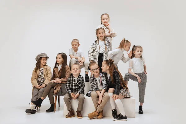 Dix enfants souriants heureux, des petites filles et des garçons dans des tenues modernes posant sur fond de studio gris. Beauté, mode enfant, éducation, concept d'enfance heureuse. — Photo