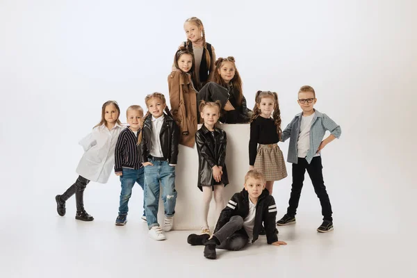 Groupe d'enfants souriants heureux, petites filles et garçons dans des tenues modernes posant sur fond de studio gris. Beauté, mode enfant, éducation, concept d'enfance heureuse. — Photo
