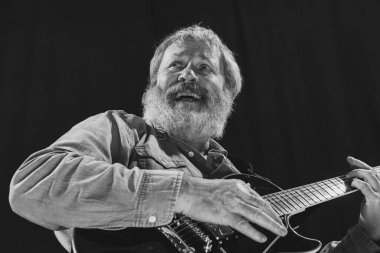 Kaliteli, son sınıf sakallı bir adam, arka planda izole edilmiş gitar çalan bir rock müzisyeni. Prova temeli: Sanat, müzik, tarz, eski nesil, klasik