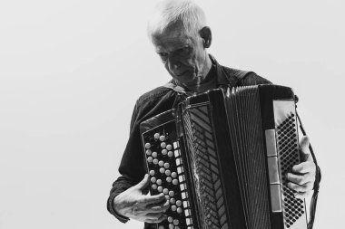 Seniot adamın tek renkli portresi, beyaz arka planda izole edilmiş akordeon çalan retro müzisyen. Sanat kavramı, müzik, tarz, eski nesil, bağbozumu