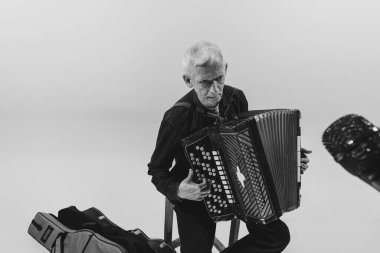 Seniot adamın tek renkli portresi, beyaz arka planda izole edilmiş akordeon çalan retro müzisyen. Sanat kavramı, müzik, tarz, eski nesil, bağbozumu