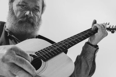 Yaşlı bir adamın siyah beyaz portresi. Müzik stüdyosunun içinde gitar çalan rock müzisyeni. Prova temeli: Sanat, müzik, tarz, eski nesil, klasik