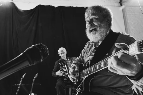 Zwei ältere Männer, Musiker mit E-Gitarre und Akkordeon. Wiederholung der Retro-Band im Musikstudio. Konzept von Kunst, Musik, Stil und Schöpfung. Einfarbig — Stockfoto