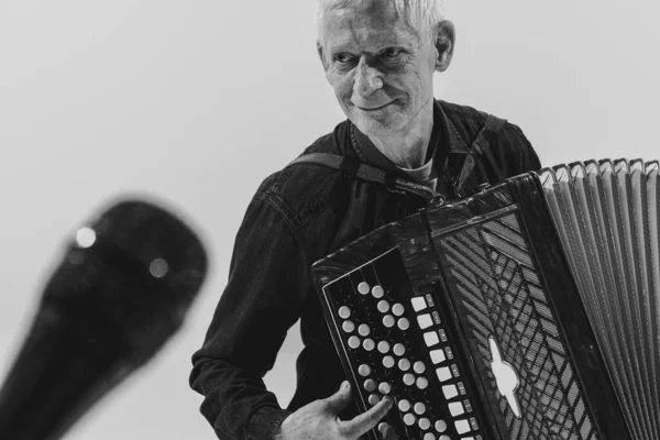 Monochrome portrait of seniot man, retro musician playing the accordion isolated on white background. Concept of art, music, style, older generation, vintage