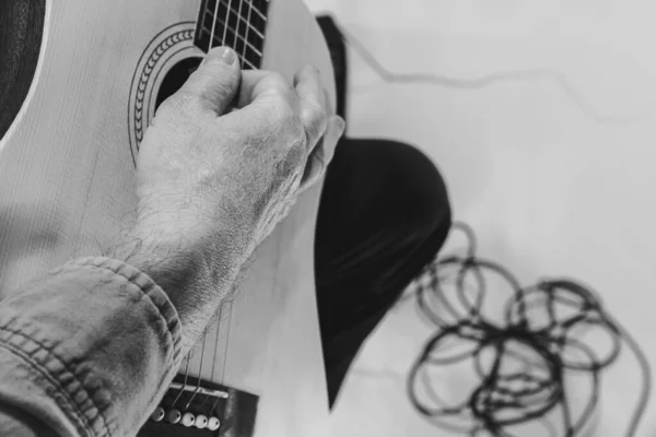 Close-up hands and acoustic guitar. Cropped monochrome portrait of man, rock musician playing guitar isolated on light background. Concept of music, style, art — 스톡 사진