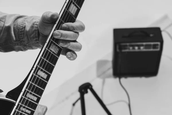 Close-up hands and electric guitar. Cropped monochrome portrait of man, rock musician playing guitar isolated on light background. Concept of music, style, art — Foto Stock