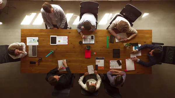 Luchtfoto van jongeren, collega 's tijdens het arbeidsproces, vergadering op kantoor, binnen. Werkzaamheden, financiën, technologie en bedrijfsconcept. — Stockfoto