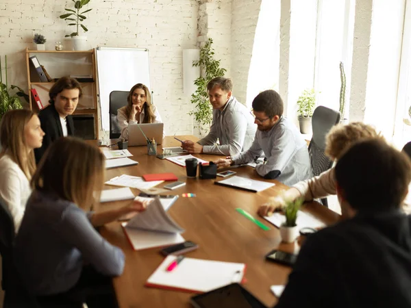 Processo de trabalho na empresa de negócios moderna. Jovens e moças discutindo algo com colegas de trabalho, sentados à mesa do escritório. Conceito de equipe, trabalho, carreira — Fotografia de Stock