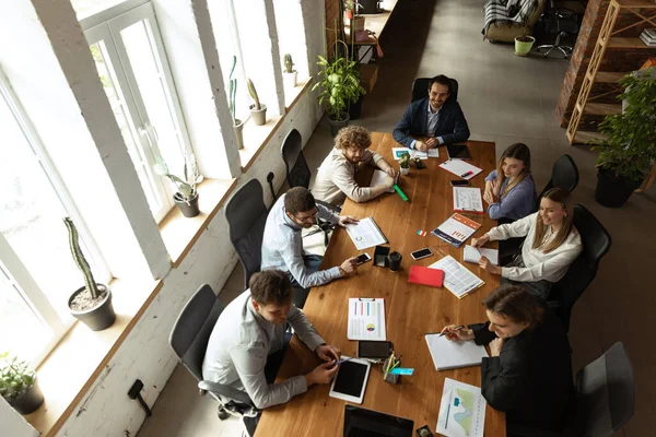 Top view of group of young people, co-workers during working process, meeting at office, indoors. Work, finance, tech and business concept. Loft style — Stock Photo, Image