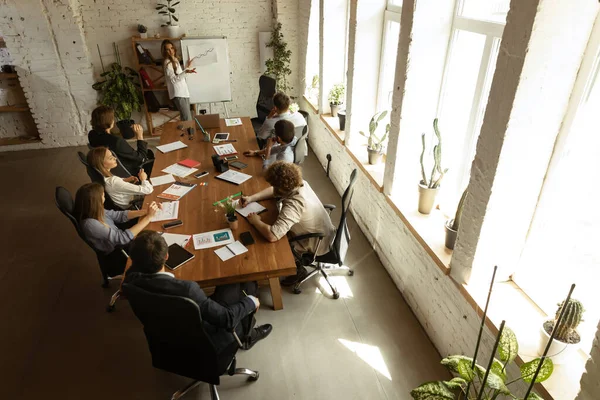 Vista superior del grupo de jóvenes, compañeros de trabajo durante el proceso de trabajo, reunión en la oficina, en interiores. Trabajo, finanzas, tecnología y concepto de negocio. Estilo Loft —  Fotos de Stock