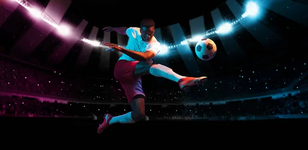 Professionele voetbal of voetbal speler in actie op het stadion met zaklampen, schoppen bal voor winnende doelpunt. Begrip sport, competitie, beweging, overwinnen. — Stockfoto