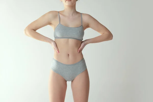 Gesneden portret van slank vrouwelijk lichaam in katoen ondergoed poseren geïsoleerd over grijze studio achtergrond — Stockfoto