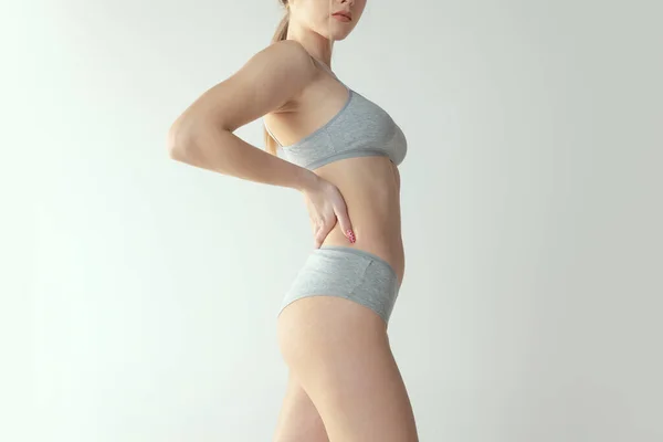 Обрезанный боковой вид портрет стройного женского тела в хлопковом нижнем белье изолирован на сером фоне студии — стоковое фото