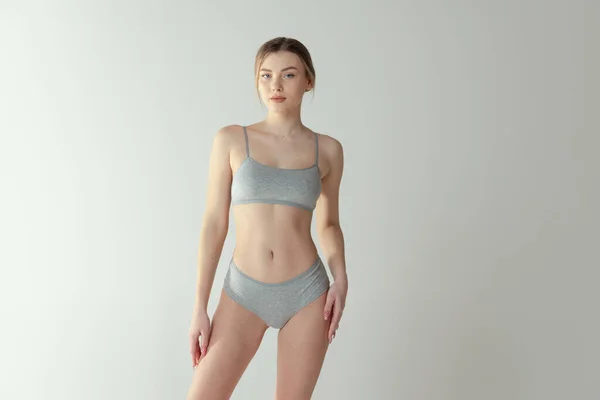 Retrato de tierna chica yound con cuerpo de ajuste tonificado posando en ropa interior aislado sobre fondo gris estudio — Foto de Stock