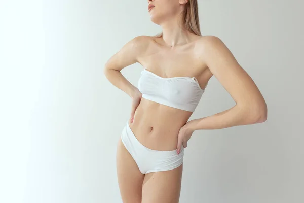 Περικοπή εικόνα του λεπτού γυναικείου σώματος σε λευκό βαμβακερό εσώρουχο απομονώνονται σε γκρι φόντο στούντιο. Φυσικότητα — Φωτογραφία Αρχείου