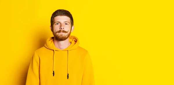 Estudio de la foto de un joven feliz hombre con capucha amarilla mirando a la cámara aislada sobre un fondo brillante. Concepto de emociones humanas, expresión facial, ventas, publicidad, moda y belleza — Foto de Stock