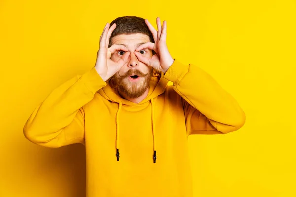 Stúdió felvétel a fiatal őrült férfi sárga kapucnis arcát, szórakozás elszigetelt fényes háttérrel. Fogalom az emberi érzelmek, arckifejezés, értékesítés, reklám — Stock Fotó