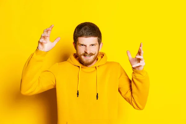 Retrato de un joven con expresión facial enojada mirando a la cámara aislada sobre fondo amarillo. Concepto de emociones humanas. — Foto de Stock