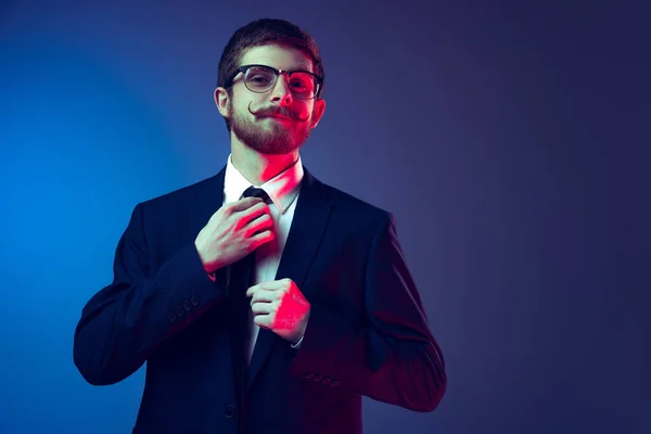 Retrato de un hombre joven y elegante en traje de negocios posando aislado sobre fondo de estudio azul oscuro. Concepto de emociones humanas, expresión facial, ventas, publicidad, moda y belleza — Foto de Stock