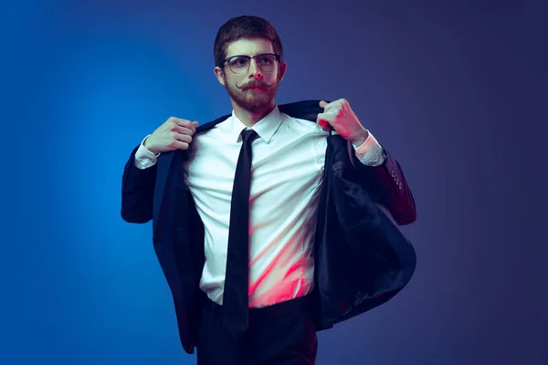 Portrait of young stylish man in business suit posing isolated on dark blue studio background. Concept of human emotions, facial expression, sales, ad, fashion and beauty — Stock Photo, Image