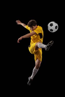 Profesyonel futbolun dinamik portresi, futbolcu eğitimi koyu arka planda izole edilmiş top. Spor, maç, aktif yaşam tarzı, hedef ve hobi kavramı