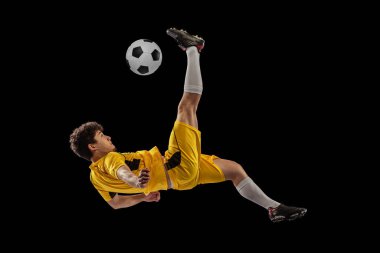 Profesyonel futbolun dinamik portresi, futbolcu eğitimi koyu arka planda izole edilmiş top. Spor, maç, aktif yaşam tarzı, hedef ve hobi kavramı
