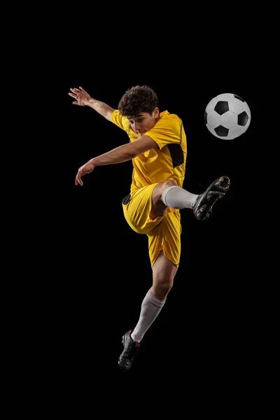 职业足球的动态肖像，足球运动员的训练与球隔离在黑暗的背景。体育、比赛、积极的生活方式、目标和爱好的概念 — 图库照片