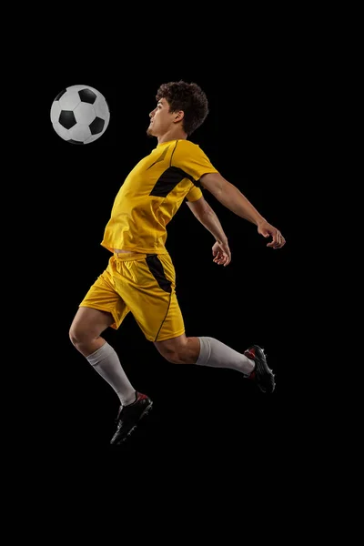 Dynamisch portret van professioneel voetbal, voetbal speler training met bal geïsoleerd op donkere achtergrond. Concept sport, match, actieve levensstijl, doel en hobby — Stockfoto