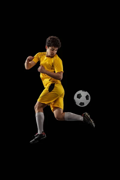 Dynamisch portret van professioneel voetbal, voetbal speler training met bal geïsoleerd op donkere achtergrond. Concept sport, match, actieve levensstijl, doel en hobby — Stockfoto