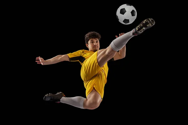 Динамічний портрет професійного футболіста, тренування футболіста з м'ячем ізольовано на темному тлі. Концепція спорту, матч, активний спосіб життя, мета і хобі — стокове фото