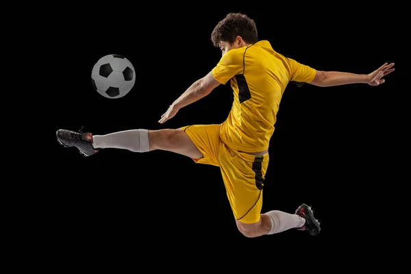 Retrato dinâmico de futebol profissional, treinamento de jogadores de futebol com bola isolada em fundo escuro. Conceito de esporte, jogo, estilo de vida ativo, objetivo e hobby — Fotografia de Stock