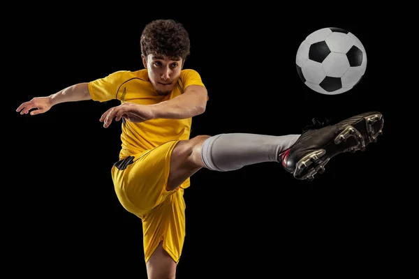 Dynamisch portret van professioneel voetbal, voetbal speler training met bal geïsoleerd op donkere achtergrond. Concept sport, match, actieve levensstijl, doel en hobby — Stockfoto