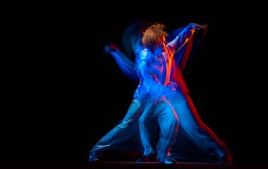 Sportif kıyafetlerle hip-hop yapan şık bir adam karanlık arka planda karışık neon ışıklarıyla dans ediyor. Gençlik kültürü, hip-hop, hareket