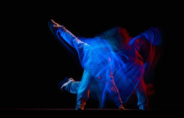 Homem elegante dançando hip-hop em roupas de estilo esportivo isolado em fundo escuro no salão de dança em luz de néon misto. Cultura juvenil, hip-hop, movimento — Fotografia de Stock