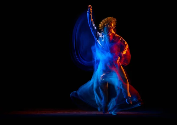 Homem elegante dançando hip-hop em roupas de estilo esportivo isolado em fundo escuro no salão de dança em luz de néon misto. Cultura juvenil, hip-hop, movimento — Fotografia de Stock