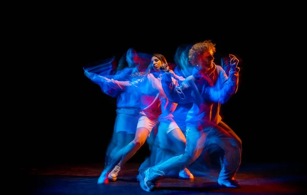 Espectáculo. Homem e menina flexíveis, dançarinos de hip-hop em movimento e ação isolados em fundo escuro no salão de dança em luz de néon misto azul. Cultura juvenil, hip-hop, movimento — Fotografia de Stock