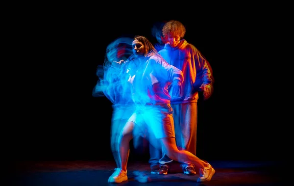 Heyecanlı erkek ve kadın karışık neon ışıklarıyla dans salonunun arka planında spor tarzı kıyafetlerle hip-hop yapıyor. Gençlik kültürü, hip-hop, hareket — Stok fotoğraf