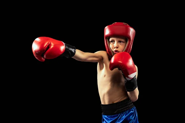 Sportif çocuğun dinamik portresi, boksör eldivenli ve şortlu çocuk koyu arka planda izole edilmiş. Spor, hareket, öğrenim, başarılar, aktif yaşam tarzı kavramı. — Stok fotoğraf