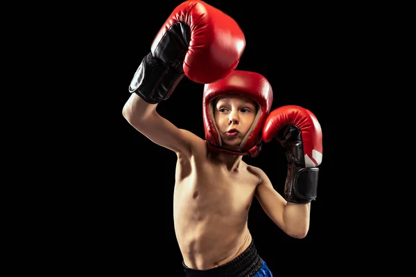 スポーツ少年、ボクサー手袋の子供のダイナミックな肖像画と暗い背景に隔離された練習のショートパンツ。スポーツ、運動、勉強、成果、アクティブライフスタイルの概念. — ストック写真