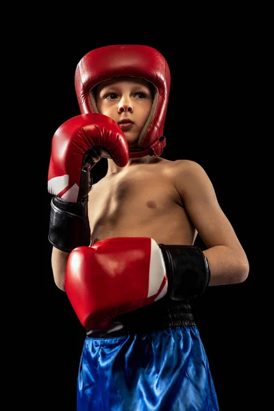 Küçük sportif çocuk, boksör eldivenli ve şortlu çocuk karanlık arka planda yalnız poz veriyor. Spor, hareket, öğrenim, başarılar, aktif yaşam tarzı kavramı. — Stok fotoğraf