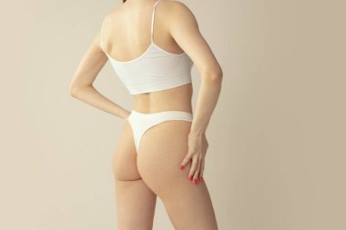 İnce kadın vücudu, gri stüdyo arka planında izole edilmiş beyaz pamuklu iç çamaşırlı kalçalar. Anti-selülit tedavisi. Güzellik, sağlık, vücut ve cilt bakımı, spa, kozmetoloji, fitness, reklam