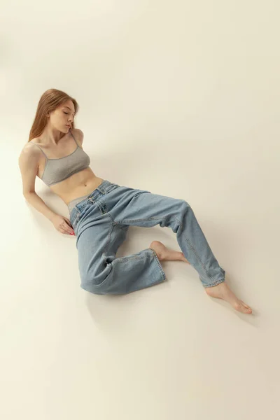 Vacker Flicka Ligger Golvet Underkläder Topp Och Jeans Poserar Isolerad — Stockfoto